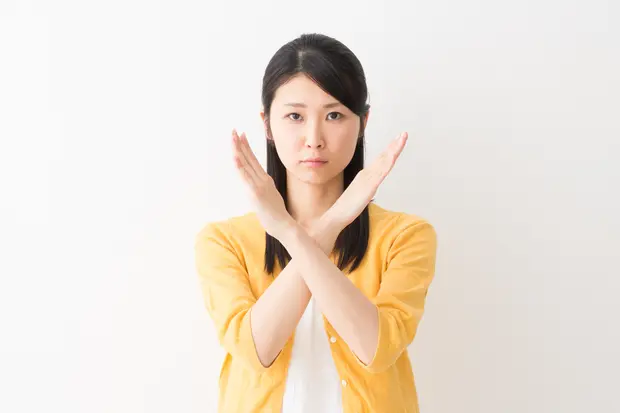 腕でバツ印を作る女性