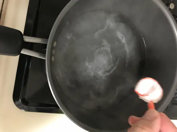 お湯に重曹の粉大さじ5〜6杯を少しずつ入れる場面