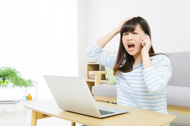 パソコンを見ながら電話をする女性