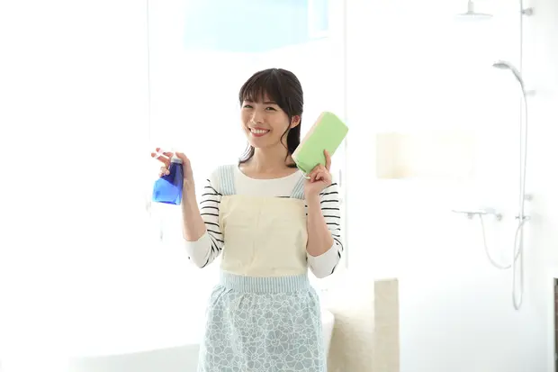 浴室で掃除道具を手に微笑む女性